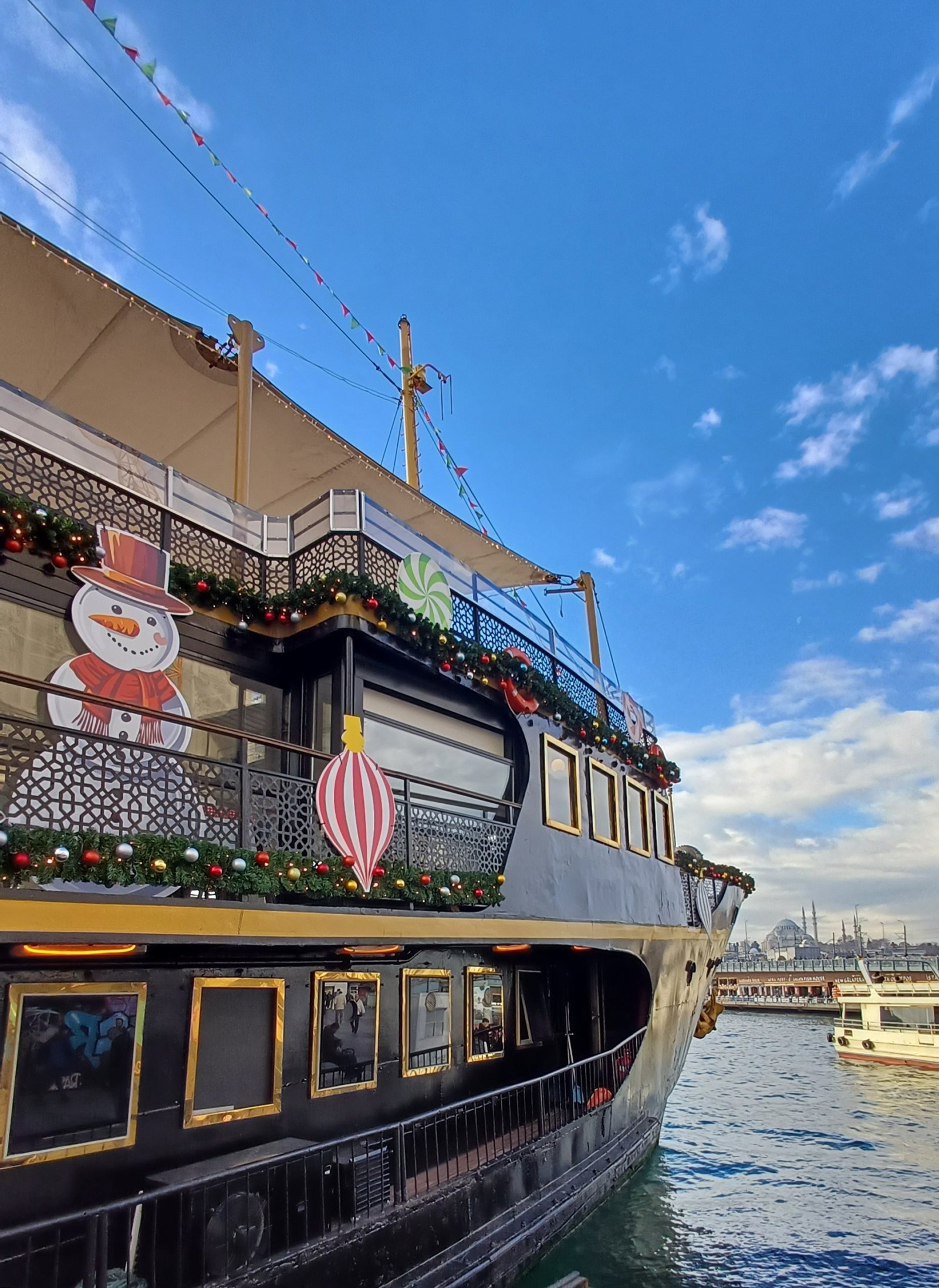 Festive Le Vapeur Magique cruise ship docked, featuring views of Istanbul’s skyline and the iconic Süleymaniye Mosque in the background.